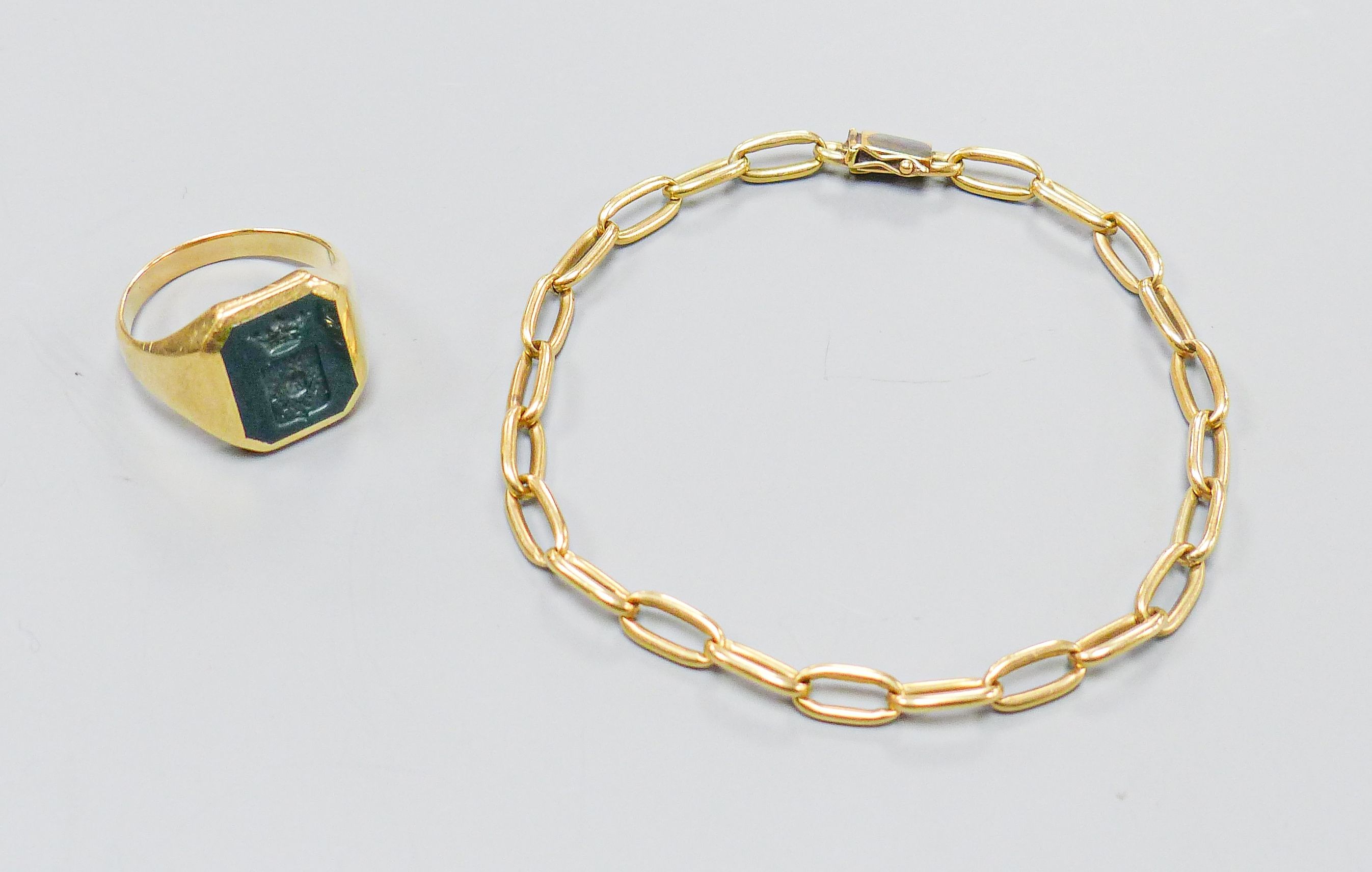 A yellow metal signet ring, inset octagonal intaglio chalcedony matrix, size U, gross 8.3 grams and a yellow metal oval-link bracelet, with box clasp, 10.5 grams.